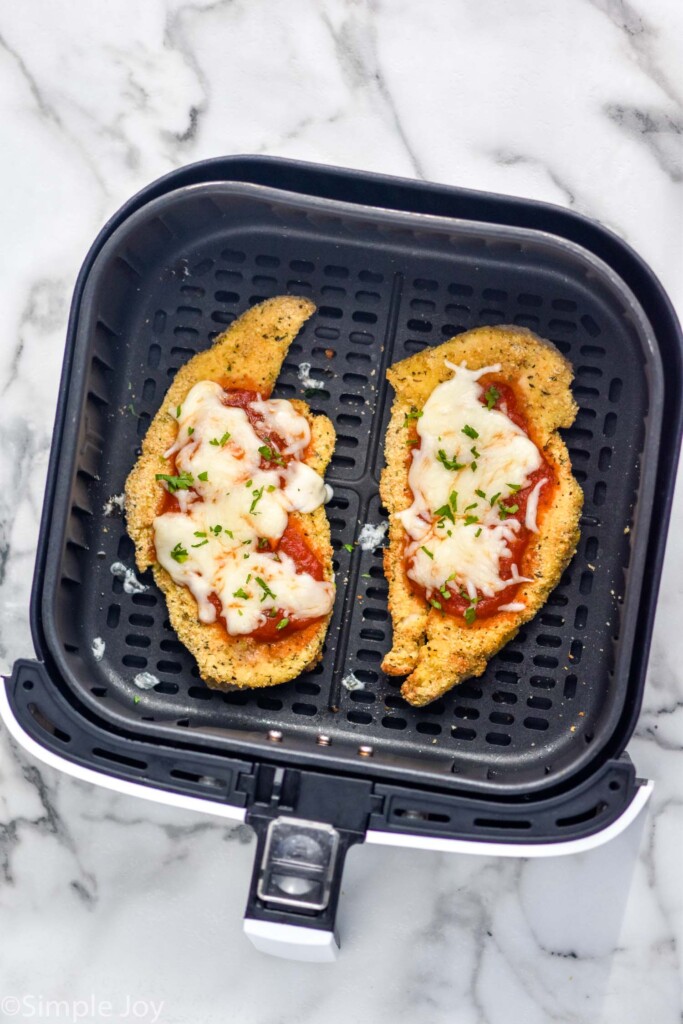 overhead of air fryer basket with two pieces of Air Fryer Chicken Parmesan