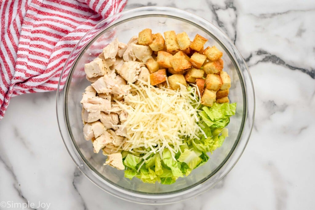 Overhead view of a glass mixing bowl of ingredients for filling for Chicken Caesar Wrap recipe