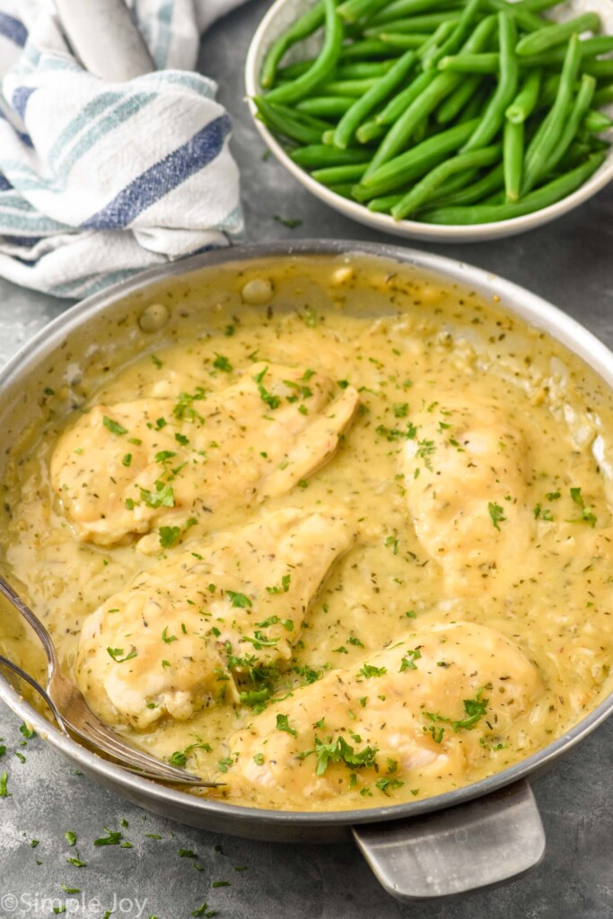 skillet of Honey Mustard Chicken with two forks and bowl of green beans sitting in background