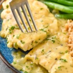 fork holding piece of honey mustard chicken on a plate with green beans and rice.