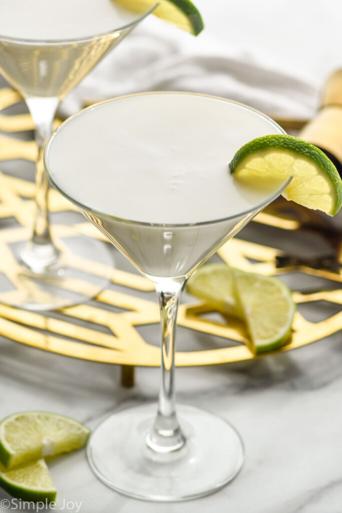 Key Lime Martini garnished with lime slice. Additional lime slices on counter beside.