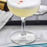 Pinterest graphic for pisco sour. Image shows coupe glass of Pisco Sour cocktail, text says "pisco sour simplejoy.com"