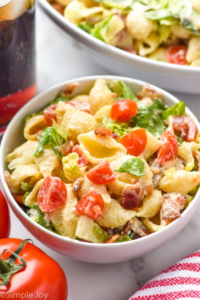 close up of a bowl of BLT Pasta Salad with tomato sitting in front