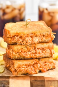 Stack of Buffalo Chicken Sandwich halves with potato chips sitting in background