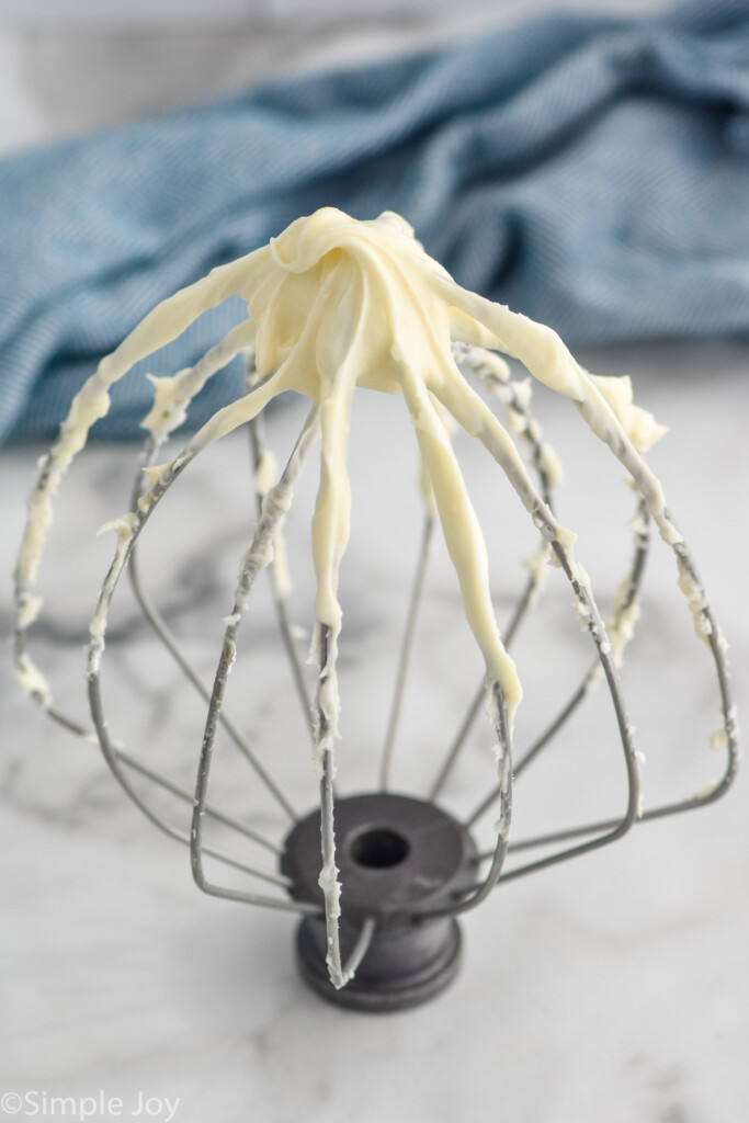 angled view of whisk attachment with cream cheese frosting