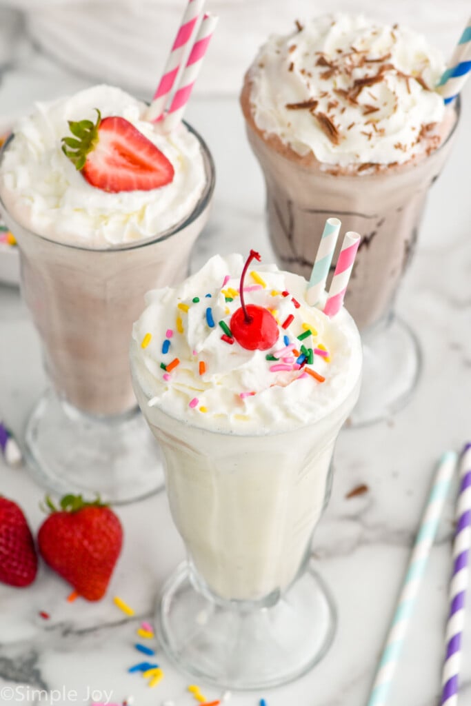 Glasses of vanilla milkshake, strawberry milkshake, and chocolate milkshake