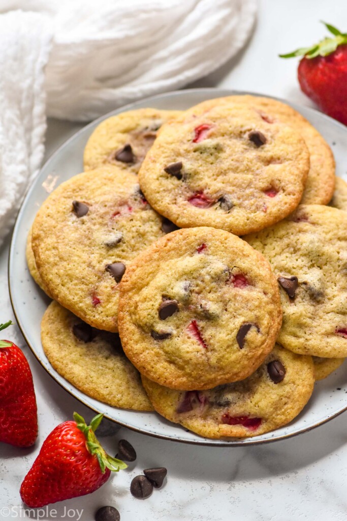 plate of Strawberry Cookies with fresh strawberries and chocolate chips sitting beside.