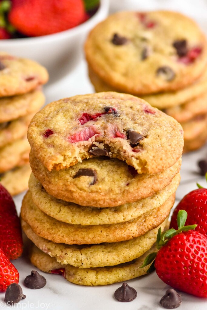 stack of Strawberry Cookies with chocolate chips and fresh strawberries sitting beside.