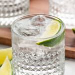 Glass of vodka press with ice and lime wedge. Two glasses of vodka press and lime wedges sitting beside.