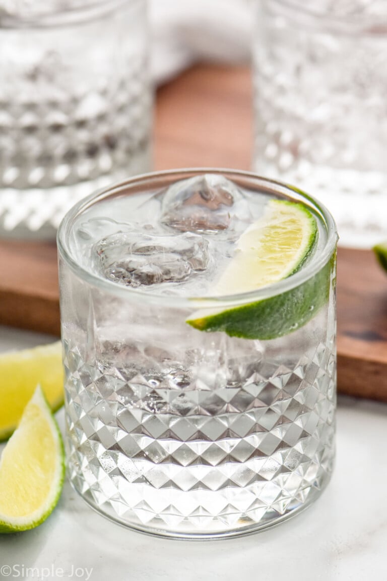 Glass of vodka press with ice and lime wedge. Two glasses of vodka press and lime wedges sitting beside.