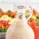 Pinterest graphic for Cajun Ranch dressing. Text says "the best cajun ranch dressing simplejoy.com" Image shows Glass jar of homemade Cajun Ranch Dressing with salad and tomatoes sitting in background