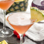 Pinterest graphic for french martini. Text says "the best French Martini simplejoy.com" Image shows a glass of french martini with a pineapple wedge garnish. Fresh pineapple and raspberries surrounding