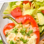 Pinterest graphic for White Chicken Chili Stuffed Peppers. Text says "crazy good White Chicken Chili Stuffed Peppers simplejoy.com" Image shows close up of White Chicken Chili Stuffed Pepper topped with fresh parsley on a plate with salad.