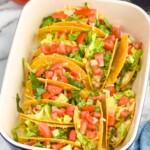 BLT Baked Tacos in a baking dish topped with diced tomatoes and lettuce