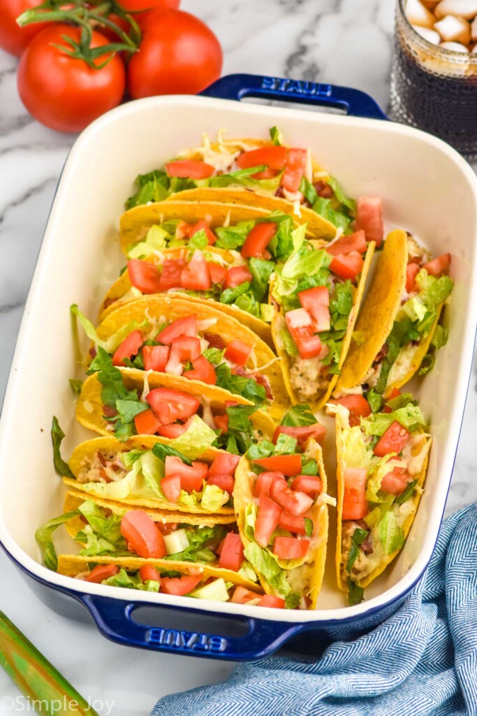 BLT Baked Tacos in a baking dish topped with diced tomatoes and lettuce