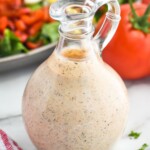 Glass jar of homemade Cajun Ranch Dressing with salad and tomatoes sitting in background