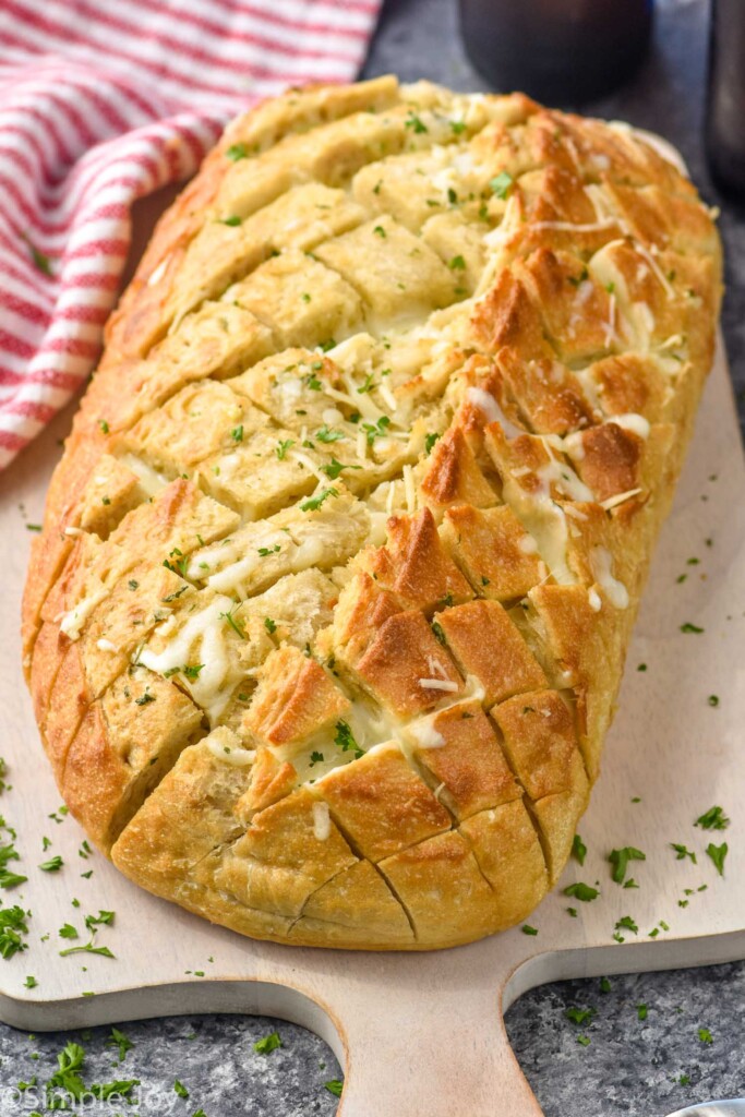 loaf of Pull Apart Bread topped with fresh parsley sitting on a cutting board