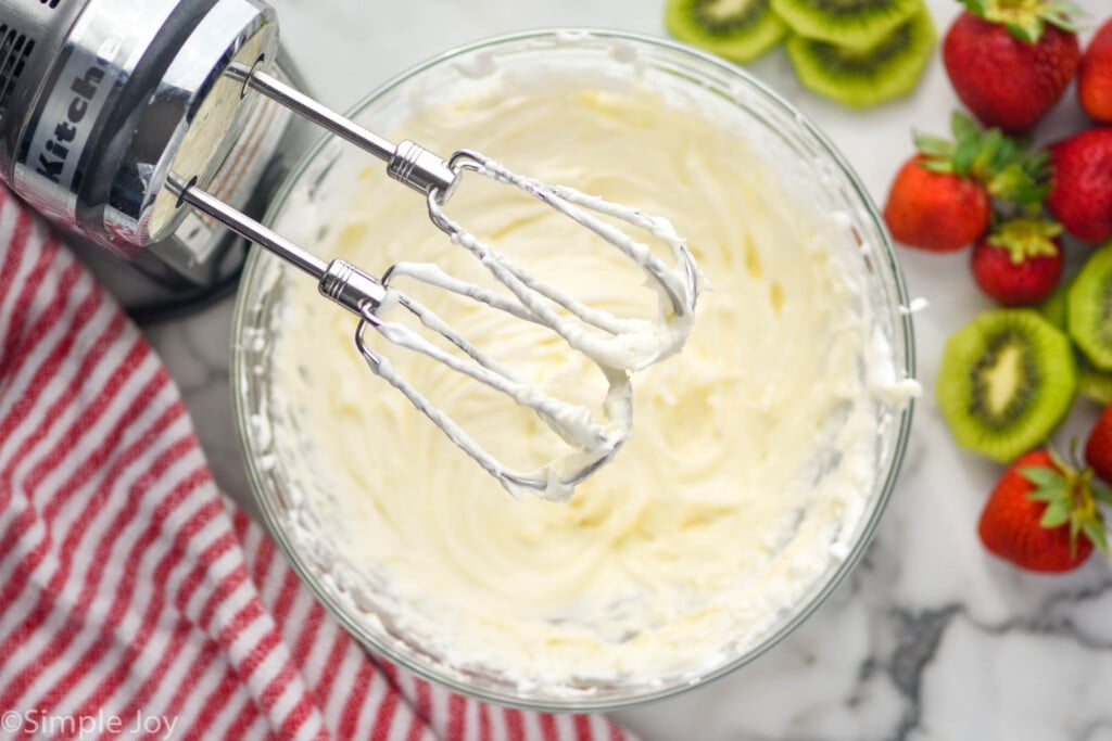 overhead of mixers over bowl of Fruit Dip with fresh kiwi and strawberries sitting beside