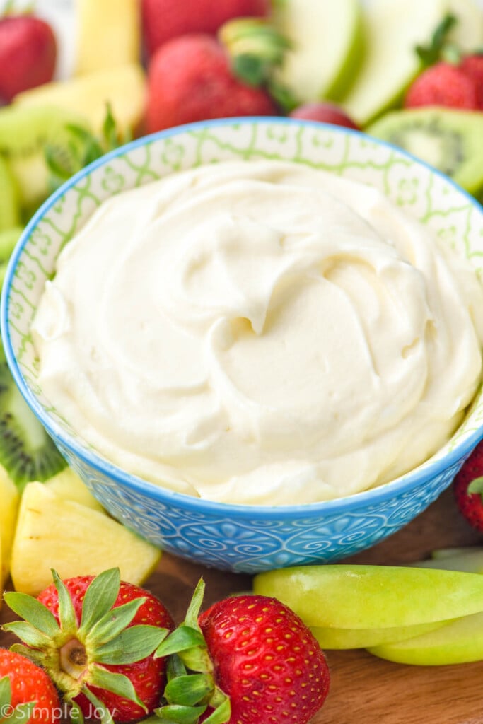 bowl of Fruit Dip surrounded by fresh strawberries, pineapple, and apple slices