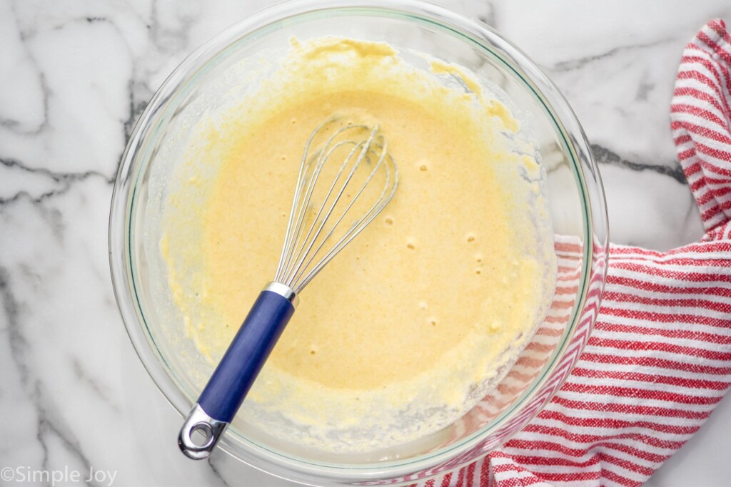 overhead of glass bowl with whisk and sauce ingredients for tamale pie