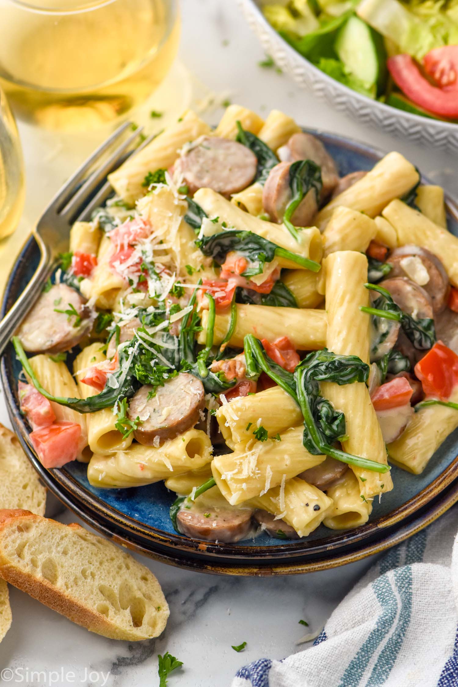 Plate of One Pot Sausage Pasta topped with freshly grated parmesan cheese and parsley with fork on the side