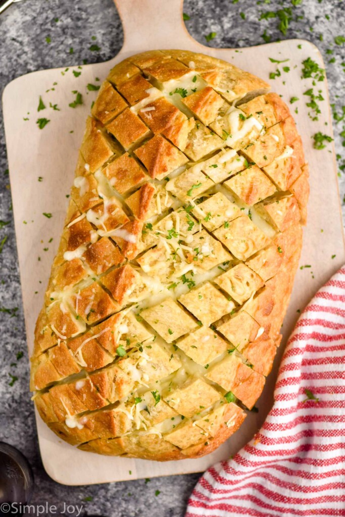 overhead of loaf of Pull Apart Bread topped with fresh parsley on a cutting board