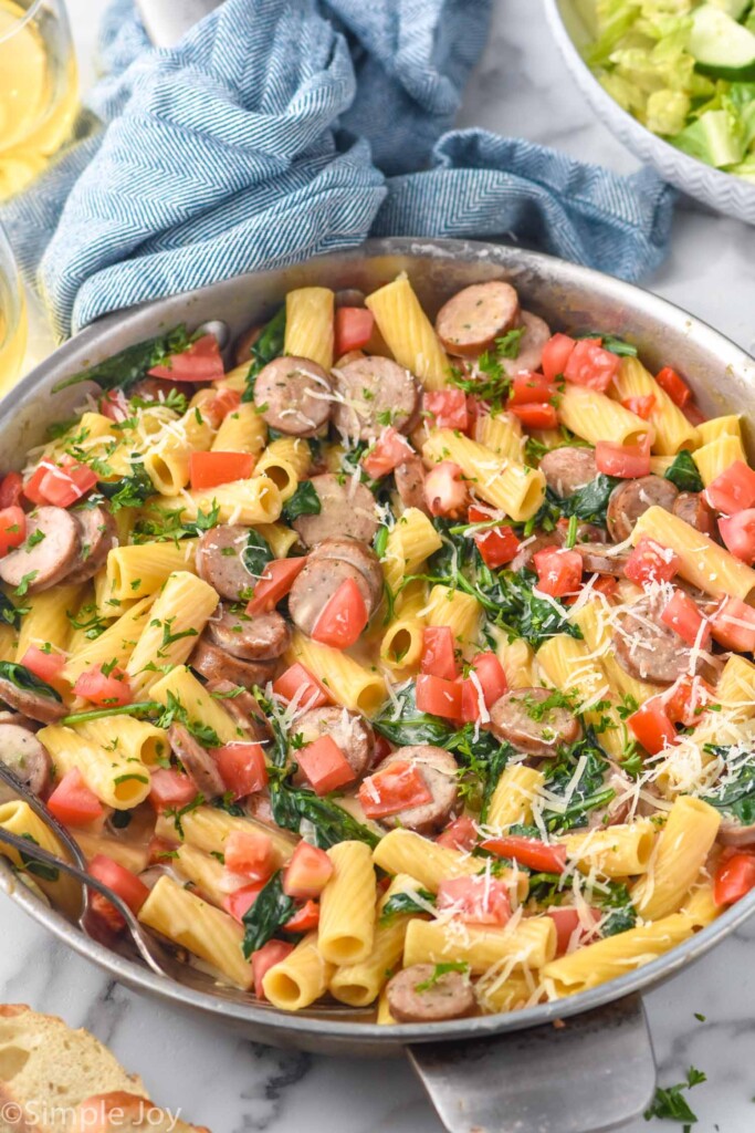 large skillet of One Pot Sausage Pasta topped with freshly grated parmesan cheese and parsley