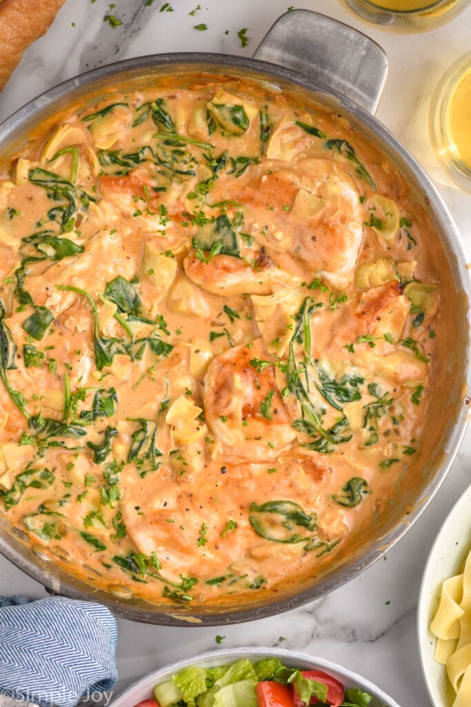 overhead of skillet of Spinach Artichoke Chicken with sauce