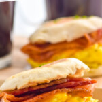 Pinterest graphic for Breakfast Sandwich. Text says "the best Breakfast Sandwich simplejoy.com" Image shows two breakfast sandwiches with bacon, eggs, and cheese on an english muffin.