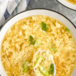 Pinterest graphic for Egg Drop Soup. Text says "the best Egg Drop Soup simplejoy.com" Image shows overhead of spoon of Egg Drop Soup with bowl of soup below.