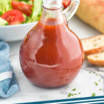 Pinterest graphic for French Dressing. Shows a jar of homemade french dressing with bowl of salad and baguette sitting behind. Says "french dressing simplejoy.com"