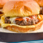 Pinterest graphic for Pizza Burgers. Image shows a pizza burger on a bun with melted cheese and pepperoni. Text says "Pizza Burgers simplejoy.com"