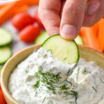 Pinterest graphic for Ranch Dip. Text says "The best Ranch Dip recipe simplejoy.com" Image shows hand holding cucumber slice into bowl of ranch dip garnished with fresh dill