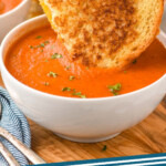 Pinterest graphic for Tomato Soup recipe. Image shows half of a grilled cheese sandwich being dipped in bowl of Tomato Soup garnished with parsley. Text says, "Tomato Soup simplejoy.com."