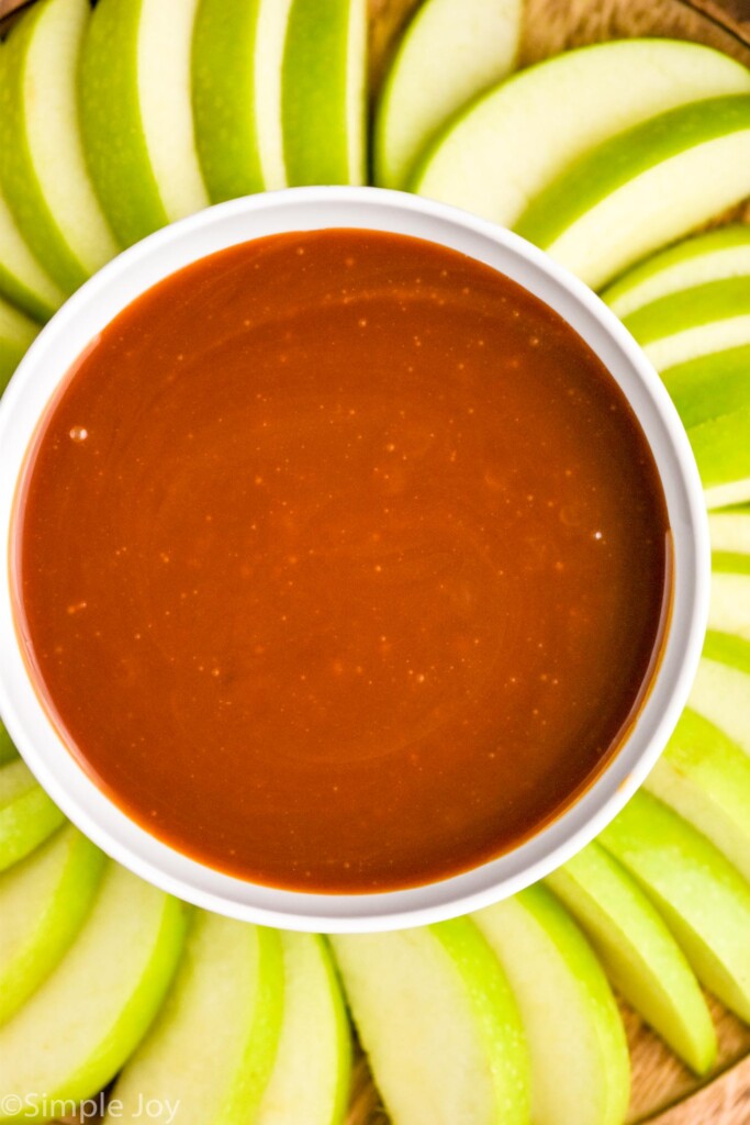 overhead of bowl of caramel apple dip with green apple slices surrounding