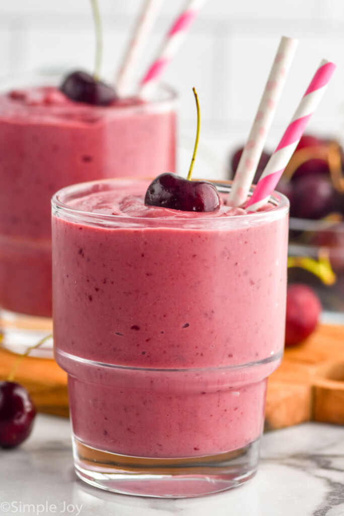 side view of a cherry smoothie recipe in a glass with a second in the back ground