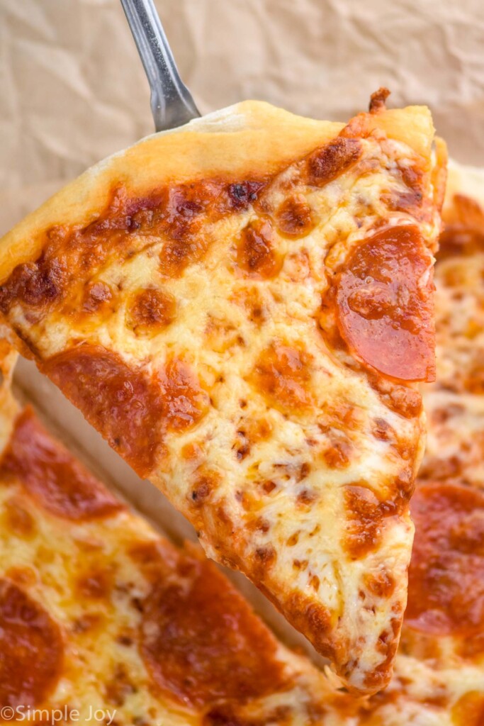 Overhead view of slice of pizza being lifted from pizza made with Pizza Dough recipe.