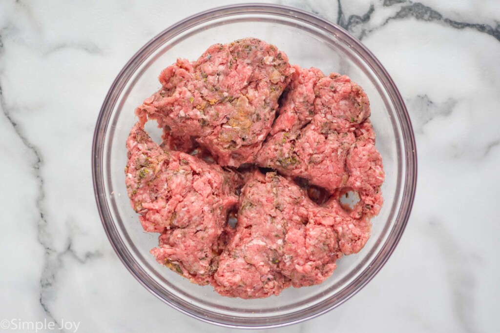 overhead of bowl of raw ground beef and spices to make pizza burgers