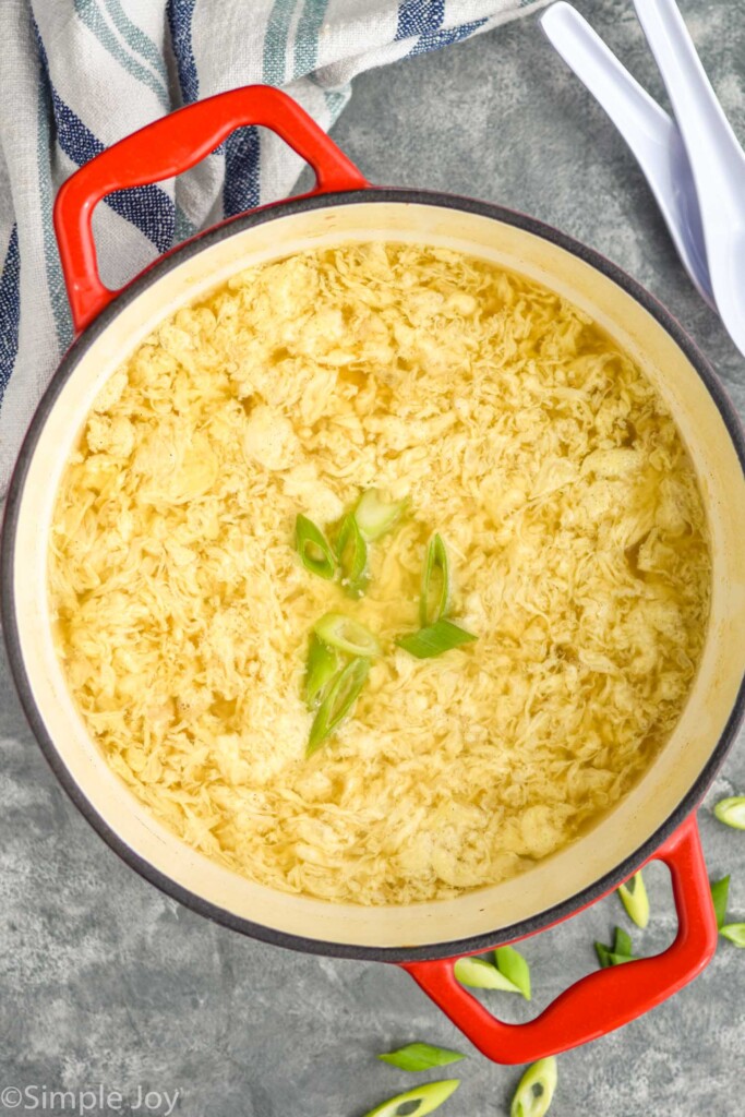 overhead of dutch oven of Egg Drop Soup topped with diced green onion