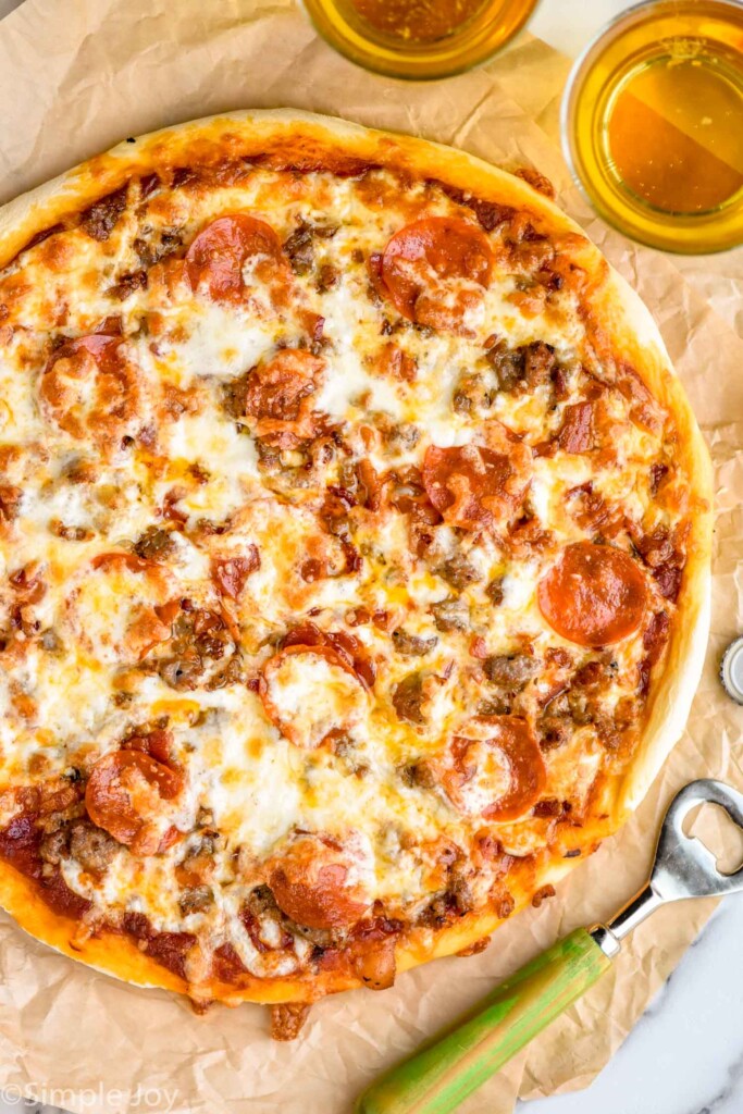 overhead of homemade Meat Lovers Pizza with two glasses of beer sitting beside