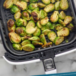 pinterest graphic for Air Fryer Brussels Sprouts. Image shows an air fryer basket of Air Fryer Brussels Sprouts. Text says "Air Fryer Brussel Sprouts simplejoy.com"