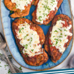 Pinterest graphic of Chicken Parmesan. Image shows overhead of plate of Chicken Parmesan topped with melted cheese and fresh parsley. Says "Chicken Parmesan simplejoy.com"