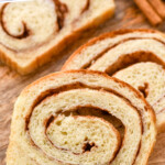 Pinterest graphic for cinnamon bread. Text says "the best cinnamon bread simplejoy.com" Image shows close up of slices of cinnamon bread with cinnamon sticks on a wooden board for serving.