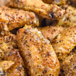 Pinterest graphic for Lemon Pepper Wings. Text says "the best Lemon Pepper Wings simplejoy.com" Image shows close up of Lemon Pepper Wings with a lemon wedge sitting in front.