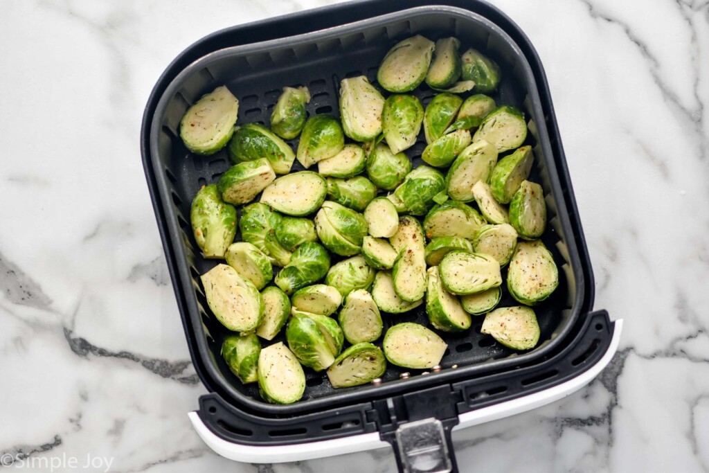 overhead of air fryer basket of seasoned brussels sprouts to make Air Fryer Brussels Sprouts