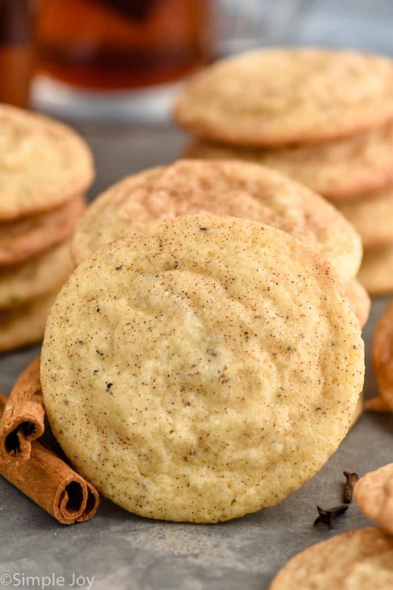 Chai Sugar Cookie with stacks of Chai Sugar Cookies and cinnamon sticks siting behind