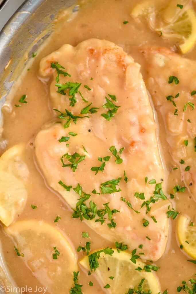 close up of Lemon Chicken in a skillet topped with fresh parsley