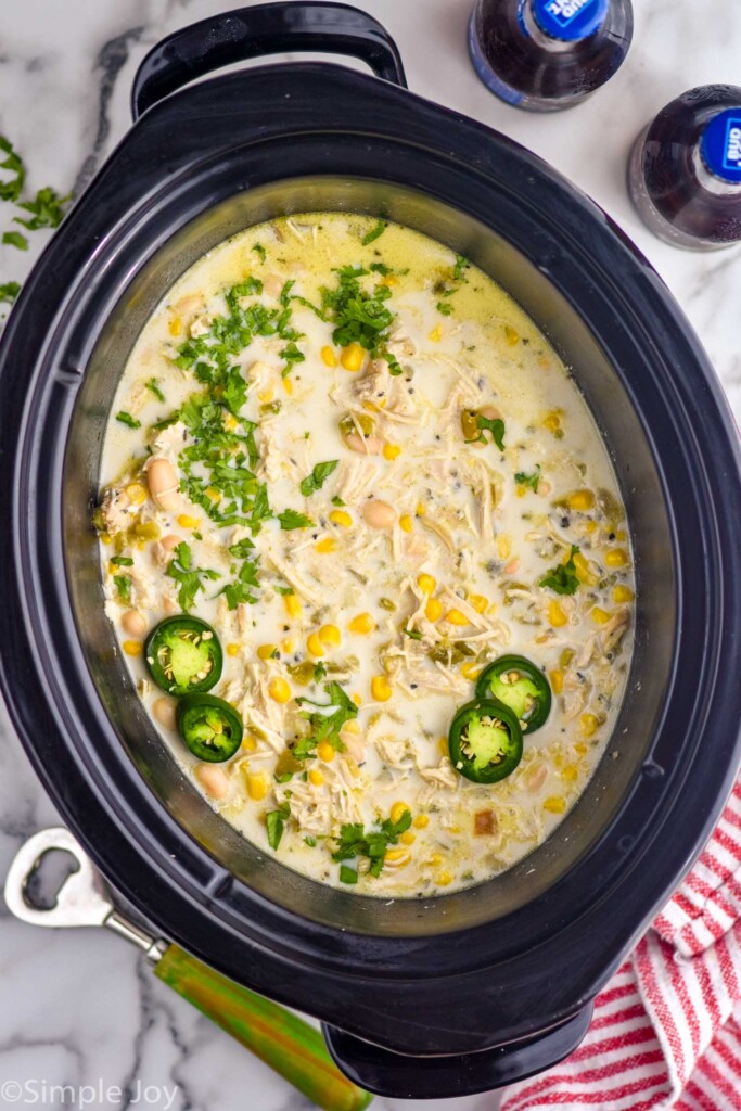 overhead of crockpot of Crockpot White Chicken Chili topped with fresh cilantro and jalapeño slices