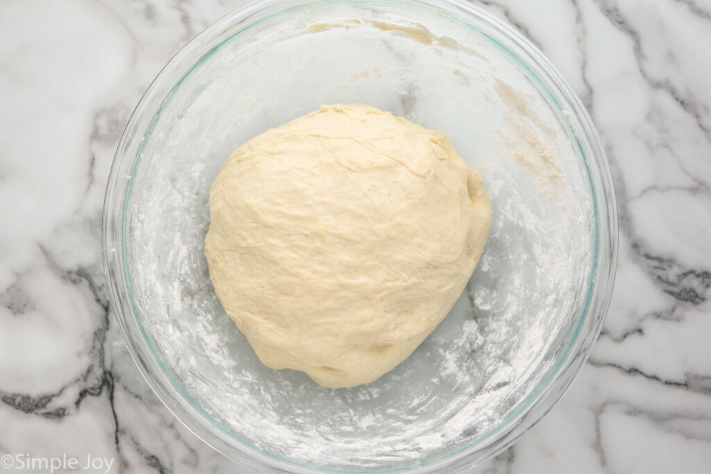 overhead of glass bowl with ball of dough to make cinnamon bread