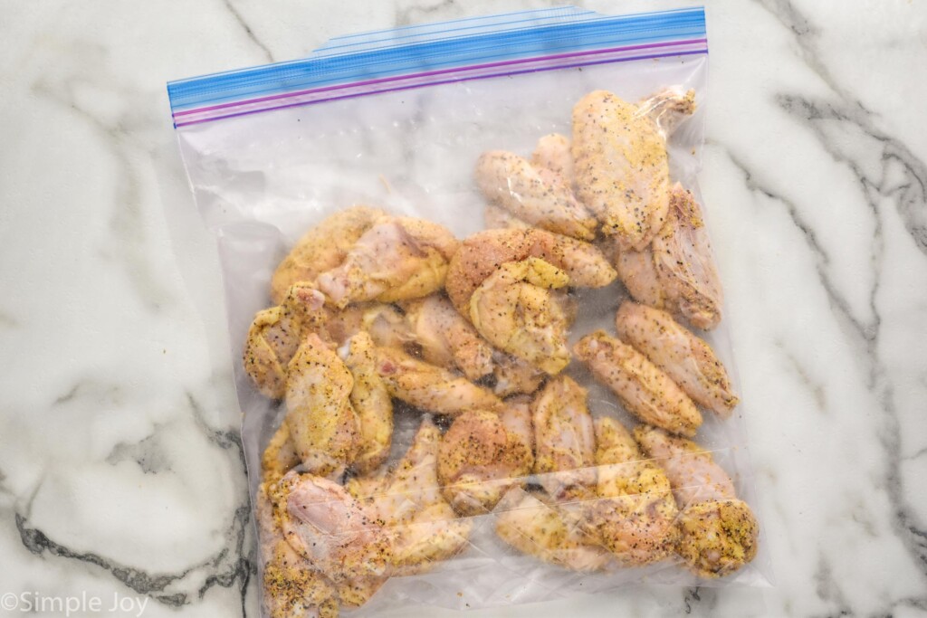 overhead of ziplock bag of chicken wings covered in lemon pepper seasoning to make Lemon Pepper Wings